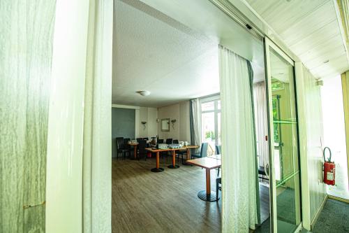 a living room with a table and a desk at Logis Hôtel - Le Relais du Parisis in Villeparisis