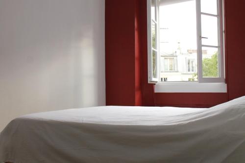 un lit blanc dans une chambre avec une fenêtre dans l'établissement Appartement dans le Marais, à Paris