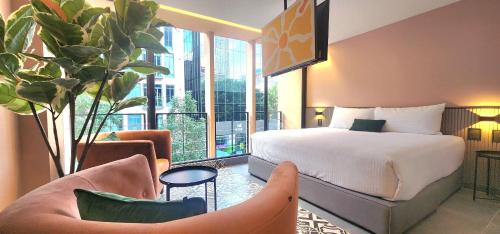 a hotel room with a bed and chairs and a balcony at NIU Reforma in Mexico City