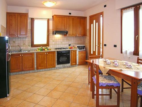 ビビオーネにあるAppartamenti Mirellaのキッチン(木製キャビネット、テーブル、椅子付)