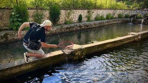 a man holding a net in the water at Cottage ,,Okatsia” ოკაციას კოტეჯები in Gordi