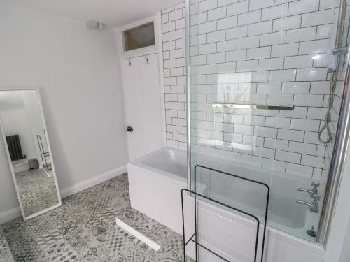 a bathroom with a glass shower and a tub at Suffolk House in Narberth