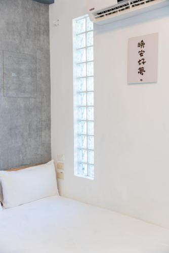 a bedroom with a white bed and a window at Moonlit Corner in Taitung City