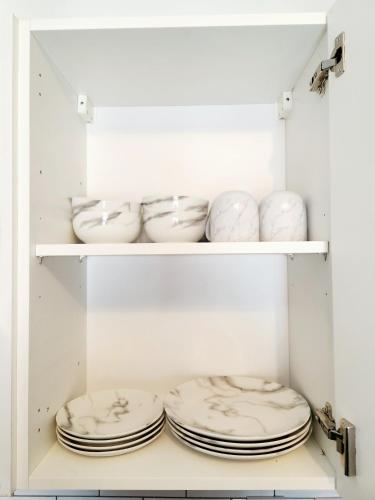 a white cupboard with plates and bowls in it at 'The Cityside Charm' - Modern, Pristine & Well-appointed 1 Bed Flat in Town - Free Parking in Northampton