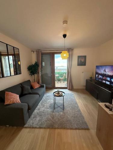 un salon avec un canapé et une télévision dans l'établissement Cosy avec terrasse à Disney, à Montévrain