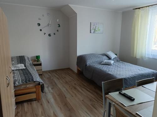 a bedroom with two beds and a clock on the wall at Chruścielówka ap nr 1 in Tylicz