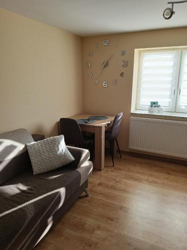 a living room with a table and a clock on the wall at Chruścielówka ap nr 1 in Tylicz