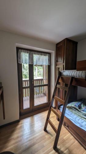 - une chambre avec des lits superposés et un balcon dans l'établissement Appartamento immerso nel verde zona tranquilla, à Auronzo di Cadore