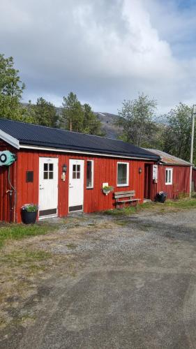 a red building with white doors and a bench at Tørfoss Gård, Hytte utleie, Campingvogn og bobil plasser in Potka