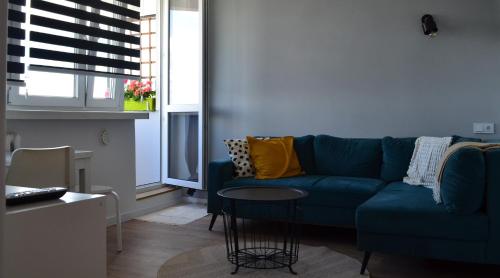 Una sala de estar con un sofá azul y una mesa. en Apartment Silesia Park - Free Parking - easy check-in, en Katowice