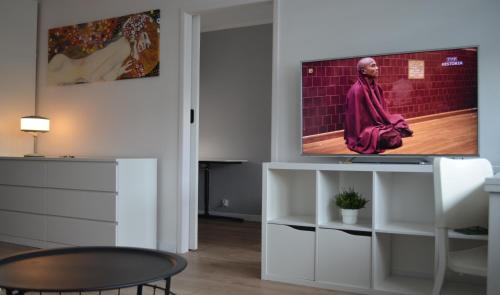 una sala de estar con TV en un centro de entretenimiento blanco en Apartment Silesia Park - Free Parking - easy check-in, en Katowice
