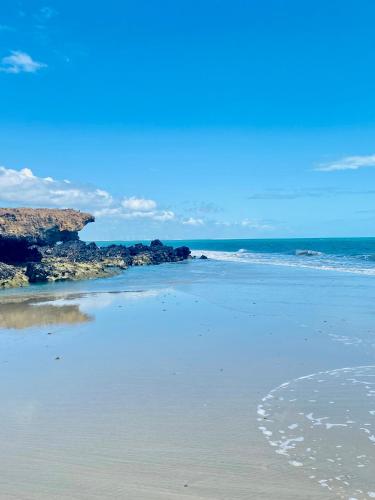 a beach with rocks and the ocean on a sunny day at Casa Calango suites in Fortim