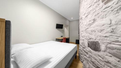 a bedroom with a white bed and a stone wall at Rija Old Town Hotel in Tallinn