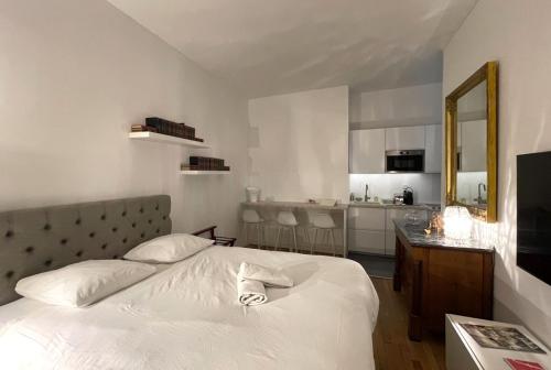 Cet appartement comprend une chambre avec un lit blanc et une cuisine. dans l'établissement Aux Clefs des Sacres - Le Talleyrand, à Reims