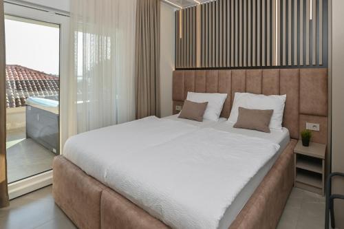 a bedroom with a large bed and a balcony at Aparthotel OLIVE with jacuzzi and breakfast in Novalja