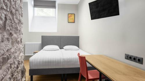 a bedroom with a bed with a wooden table and a window at Rija Old Town Hotel in Tallinn