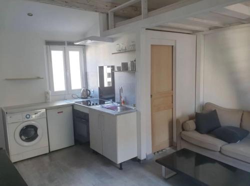 une cuisine avec un lave-linge et un canapé dans l'établissement Charmant studio Chartreux, à Marseille