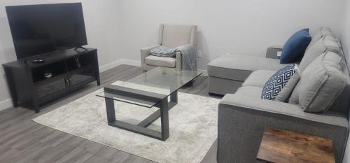 a living room with a couch and a tv and a table at A Cozy home away from home at South East Calgary in Calgary