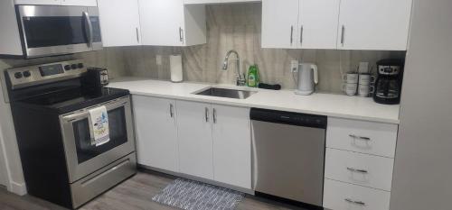 カルガリーにあるA Cozy home away from home at South East Calgaryのキッチン(白いキャビネット、シンク、コンロ付)