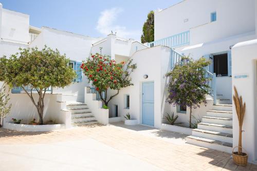 een rij witte gebouwen met bomen en een blauwe deur bij Villa Porto Rondo in Agios Prokopios