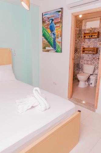 a room with a bed and a picture of a bird on the wall at Hostal Las Guaduas in Santa Marta