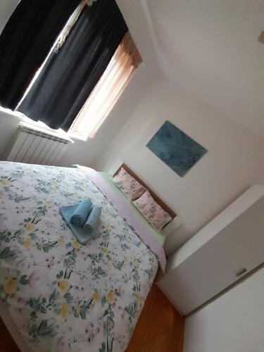 a bedroom with a bed with a floral bedspread and a window at Apartment Ken in Surčin