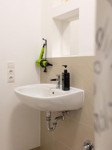 a white sink in a bathroom with a banana on the wall at Stilvolle Wohnung in Aachen Brand mit Terrasse in Aachen