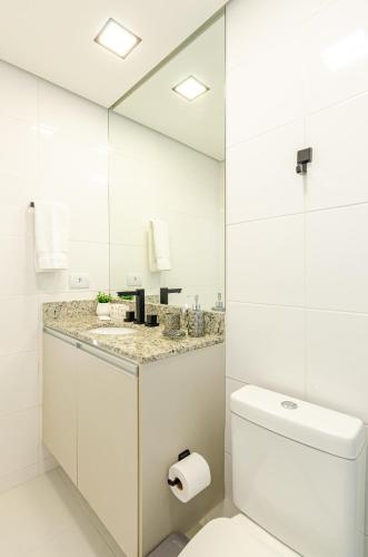 a white bathroom with a toilet and a sink at Lifespace 7 Setembro - Apartamentos UROOMS in Curitiba