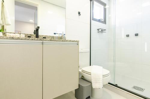 a white bathroom with a toilet and a shower at Lifespace 7 Setembro - Apartamentos UROOMS in Curitiba