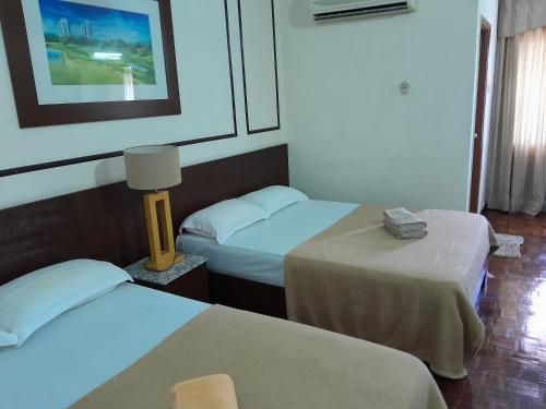 Una habitación de hotel con dos camas y una lámpara. en Jalan Kamus, Simpang Empat Holiday home, en Kampong Pulau Sebang