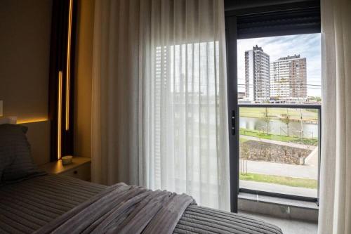 a bedroom with a bed and a large window at Apto 306 Inn com vista Parque Una e garagem in Pelotas