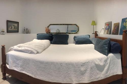 Elle comprend un grand lit avec des oreillers bleus. dans l'établissement Un jardin près de la plage, à Hyères