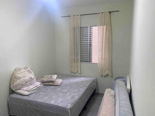 a small bedroom with a bed and a window at Apartamento Centro - Jardim Caiahu - in Mongaguá