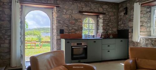 - une cuisine avec une cuisinière et une porte ouverte dans l'établissement Maison au calme au bord de l'eau, à Marzan