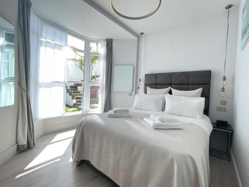 a white bedroom with a large bed with two towels on it at Henrys in St Ives