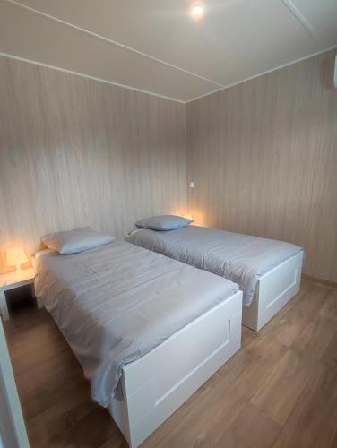 two beds in a room with wooden walls at Ben Chalet in Carlux