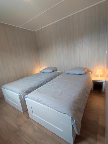 a bedroom with two beds and a table with a lamp at Ben Chalet in Carlux