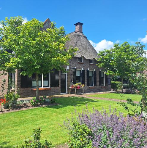 an old house with a thatched roof and a yard at B&B De Meidoornhof in Ruinen