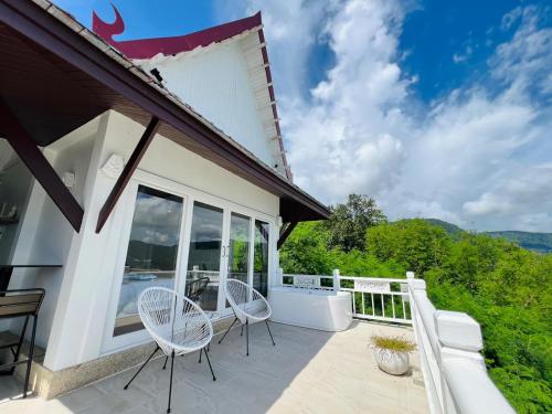 a patio with two white chairs on a balcony at Moonlight Panorama Seaview House by RESAVA in Surin Beach