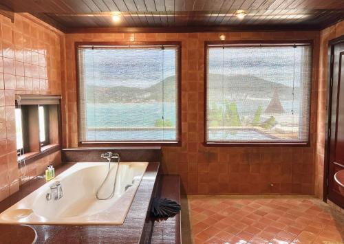 a large bathroom with a tub and two windows at Moonlight Panorama Seaview House by RESAVA in Surin Beach