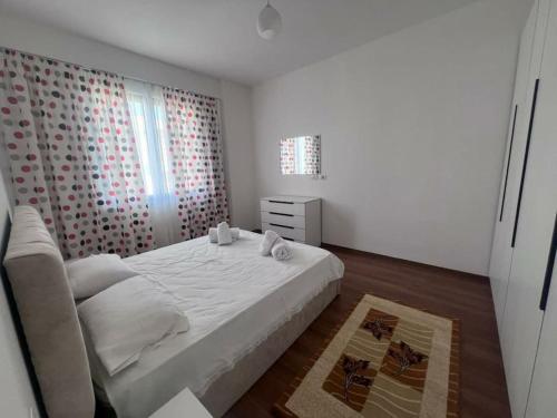 a white bedroom with a bed and a window at Pegasus luxury 1 in Tirana