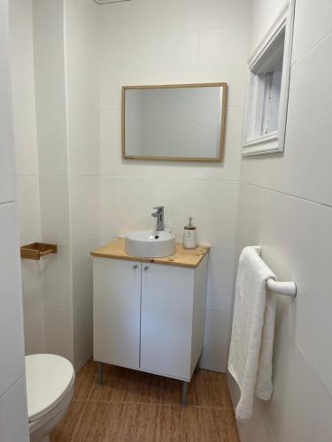 a white bathroom with a sink and a toilet at Casa do Areal in Laxe