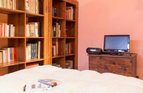 a room with a bed and a tv on a dresser with books at Camera privata con cucina in Nettuno
