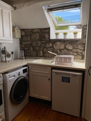 a kitchen with a sink and a washing machine at Cosy Llangynidr apartment in Llangynidr