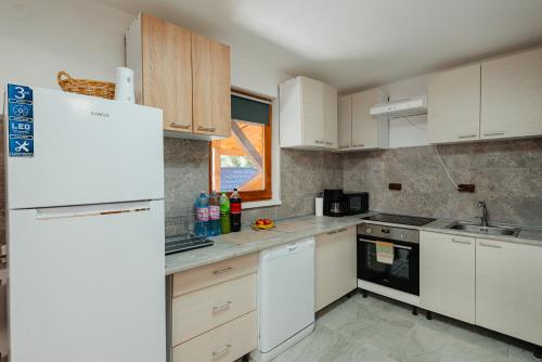 a kitchen with white cabinets and a white refrigerator at Perla Lacului in Rişca