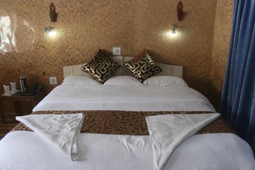 a bedroom with two beds with white sheets and pillows at Siachen Hotel in Kargil