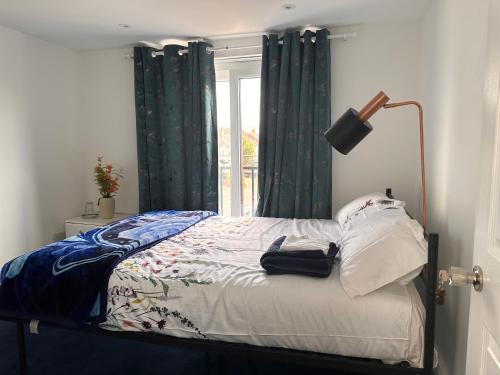 a bedroom with a bed with green curtains and a window at Quiet room in Hornchurch near Romford station on Elizabeth line to and from Heathrow airport in Romford