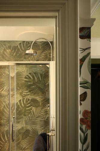 a glass door of a shower with a tropical wallpaper at The Dundrum Inn B&B in Dundrum
