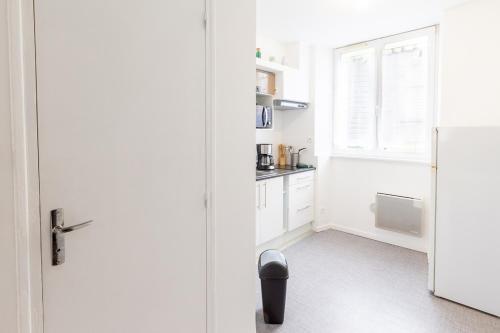 une cuisine blanche avec un réfrigérateur et une fenêtre dans l'établissement Le Littoral, à Brest