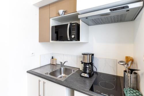 une cuisine avec un évier et un micro-ondes dans l'établissement Le Littoral, à Brest